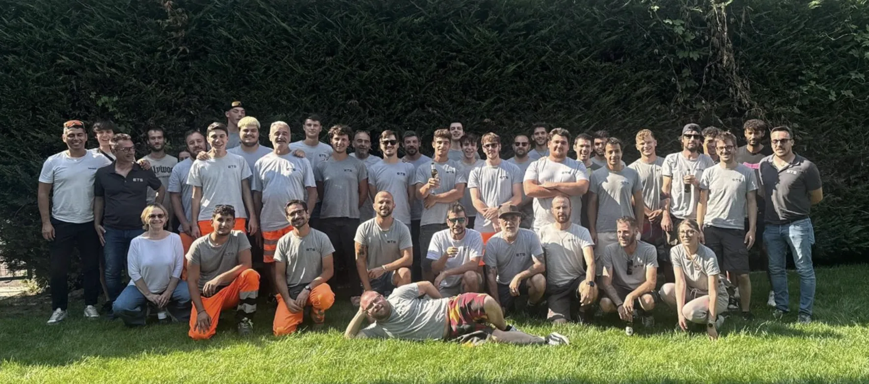 Foto di gruppo della squadra su un prato, davanti a una siepe