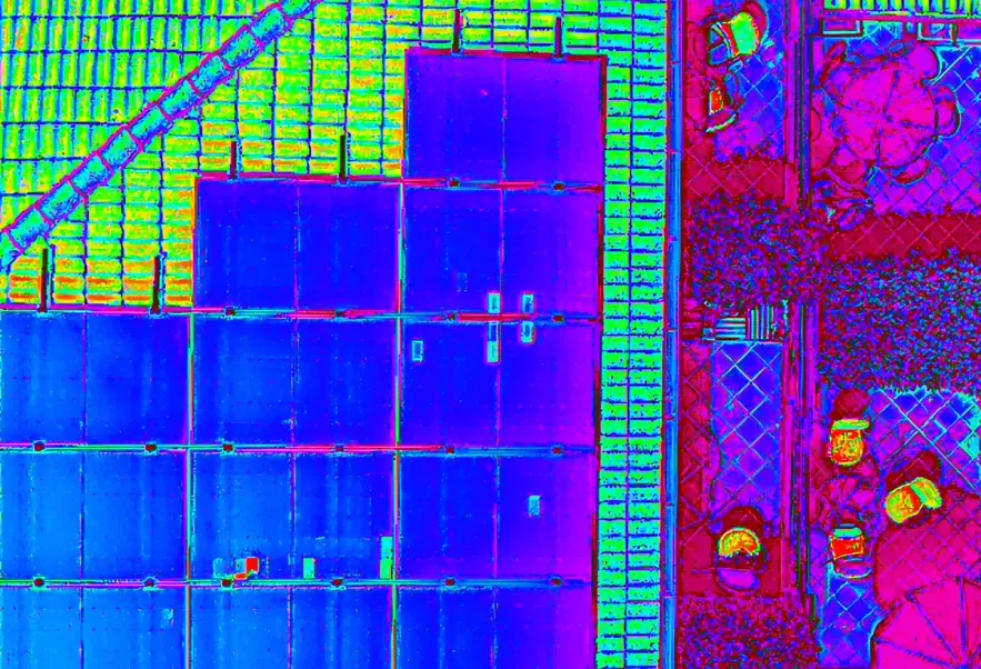 Immagine termica ripresa dall’alto di un tetto in coppi con pannelli fotovoltaici e di un terrazzo con vasi e un ombrellone