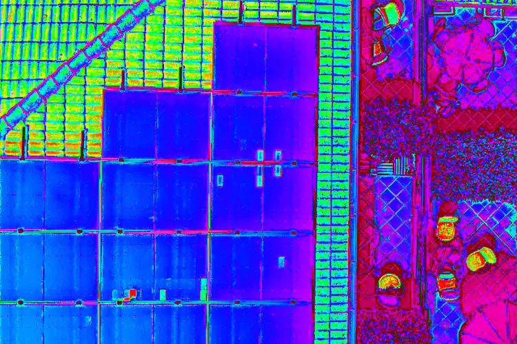Immagine termica ripresa dall’alto di un tetto in coppi con pannelli fotovoltaici e di un terrazzo con vasi e un ombrellone
