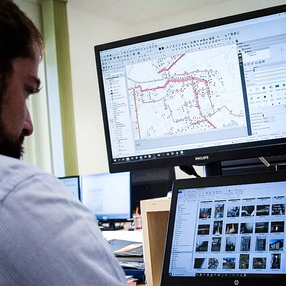 Tecnico davanti a un monitor con la mappa di una rete e a un portatile con una galleria di foto